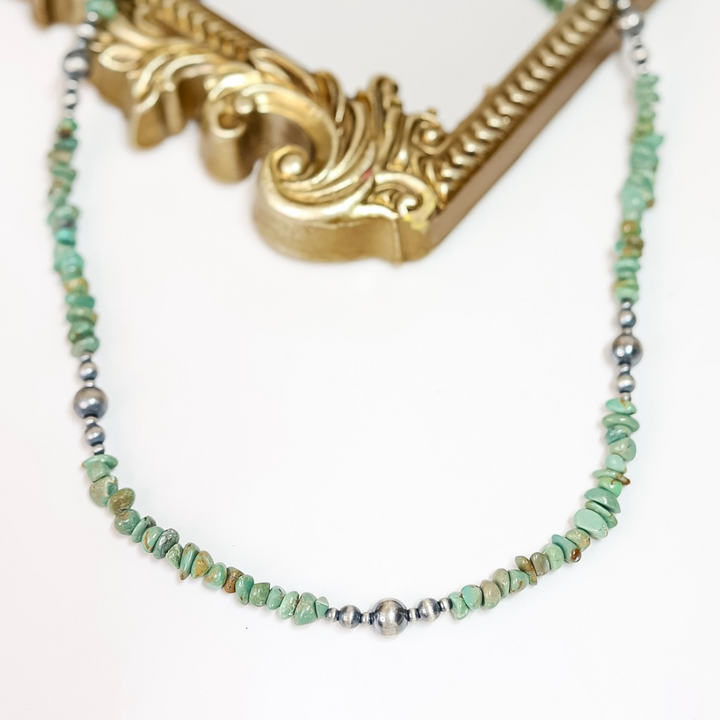 Handmade necklace featuring natural Red River Turquoise chips and sterling silver Navajo pearls, styled on a gold ornate frame with a white background.