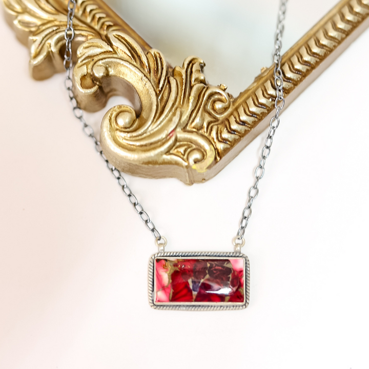 Necklace with a red and gold pendant on a decorative gold frame.