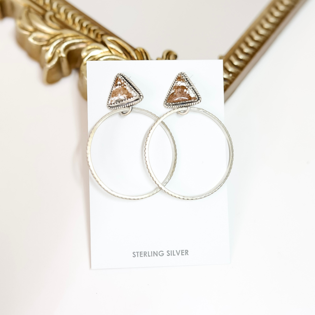 Pair of silver hoop earrings with triangle-shaped top on a white card, with 'Sterling Silver' text.