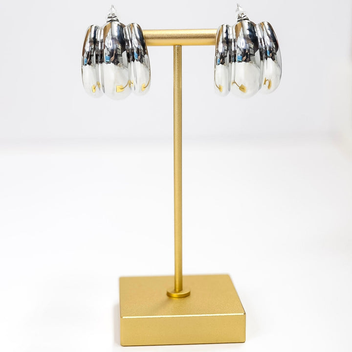 Gold jewelry stand with black and white earrings on a white background