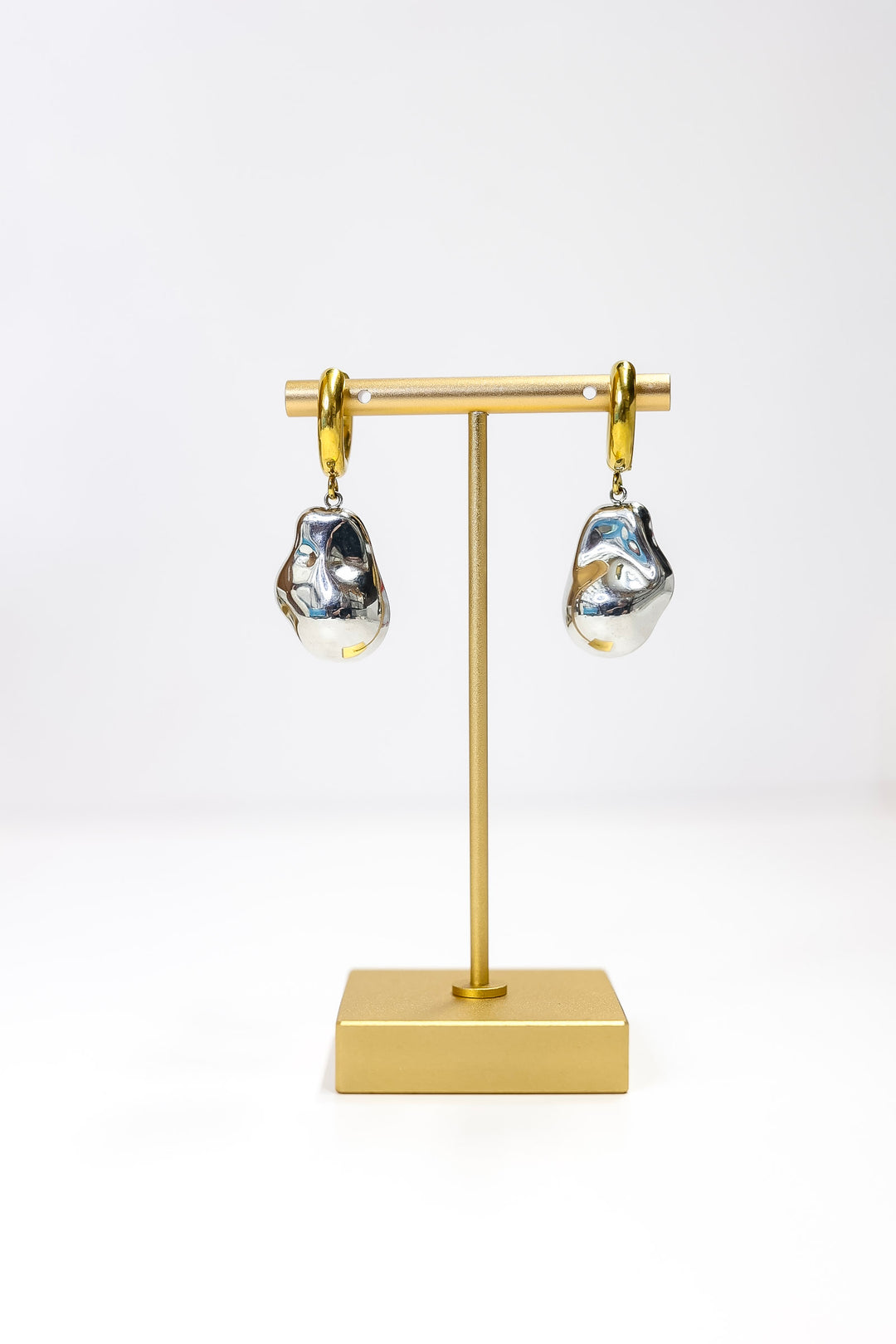 Pair of earrings on a gold stand against a white background