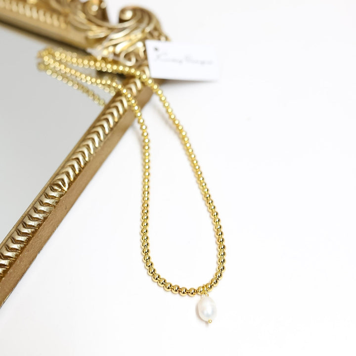 Gold chain with a pearl pendant on a white background