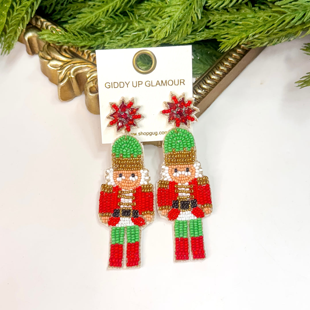 Nutcracker-themed earrings on a 'Giddy Up Glamour' card with greenery in the background