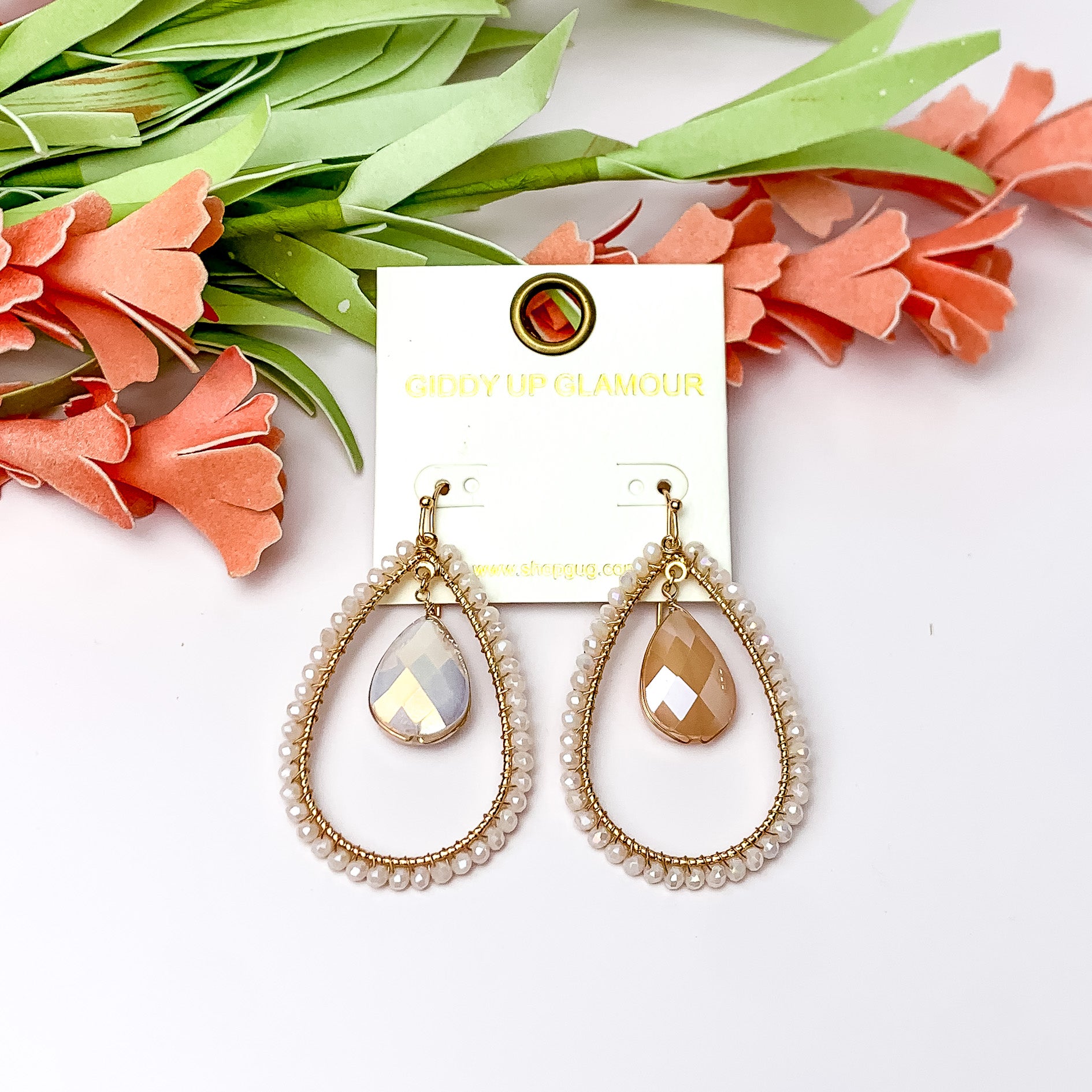 Ivory Stone Inside Open Beaded Teardrop Earrings with Gold Tone Outline. Pictured on a white background with flowers at the top.
