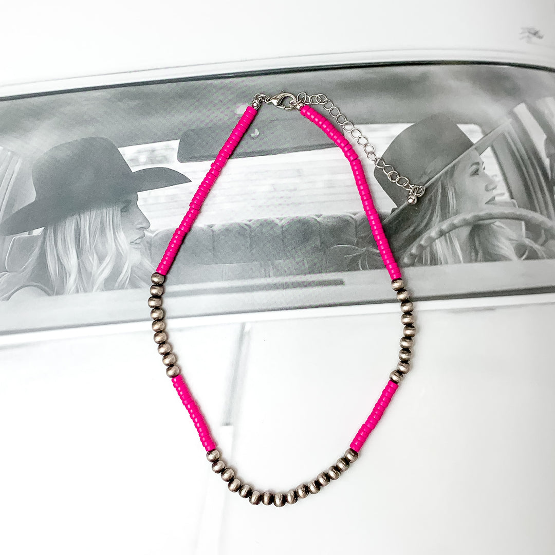 Fuchsia pink chip beaded necklace with faux Navajo pearls there are about nine next to each other on each side and one at the bottom. Pictured on a black and white photo.