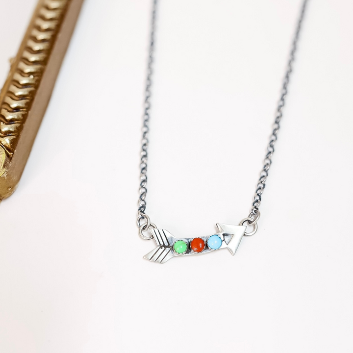 Necklace with a fish-shaped pendant featuring colorful stones on a white background