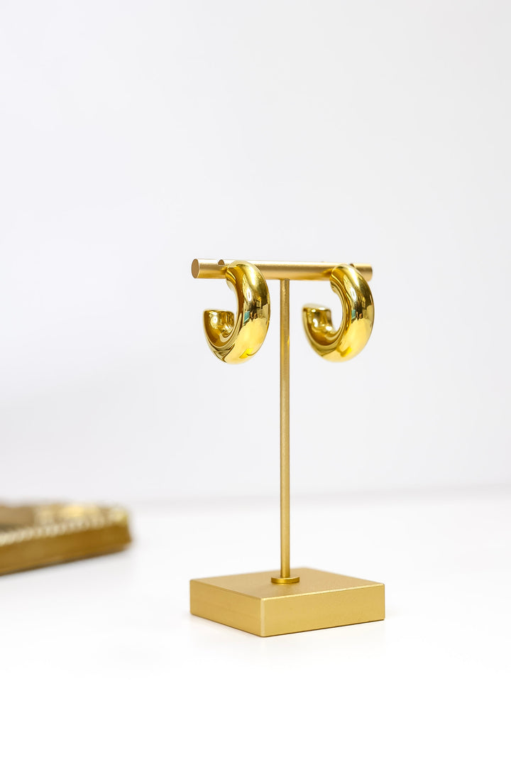 Gold earring stand with hoop earrings on a white background