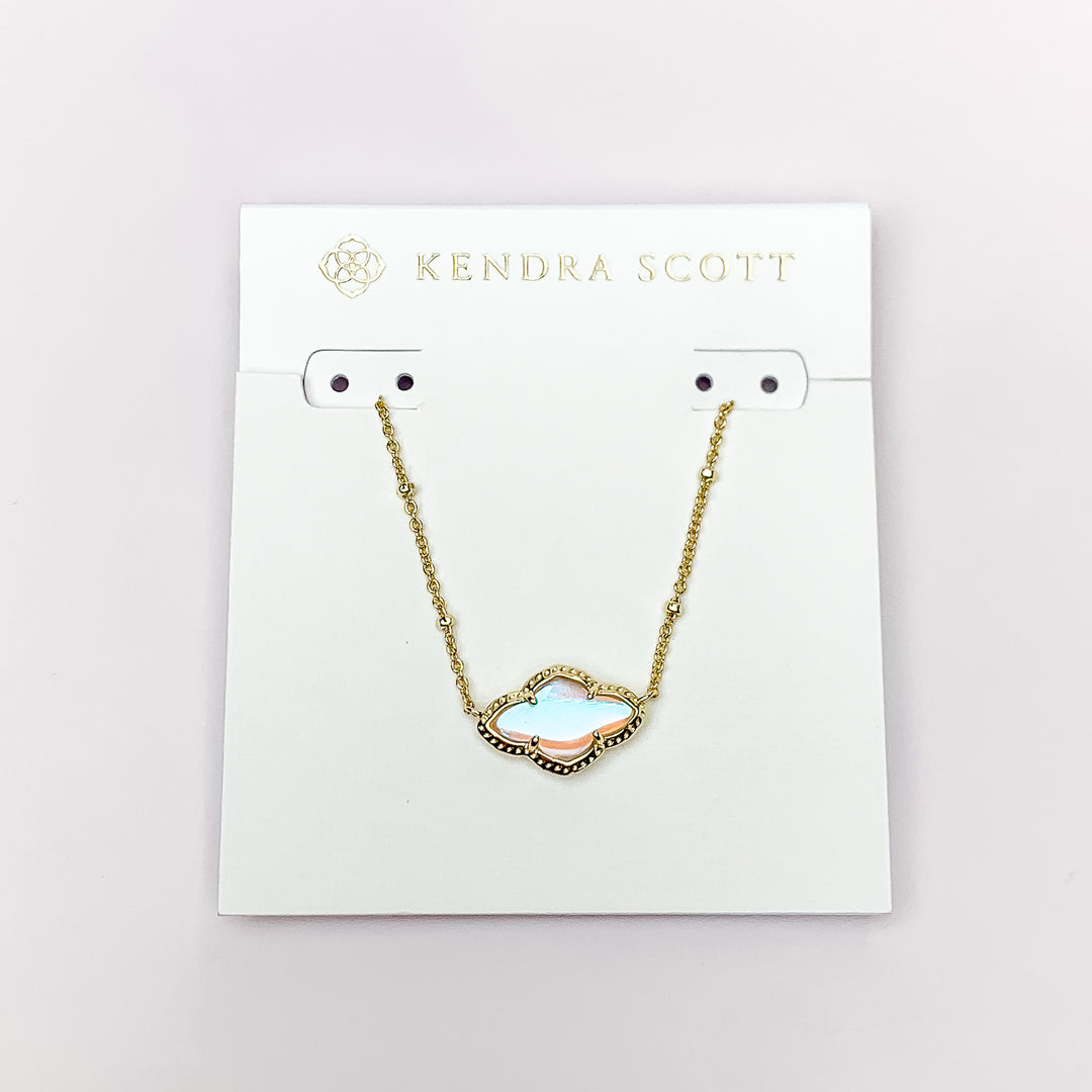 Gold chain necklace with a gold quatrefoil pendant and dichroic glass. This necklace is pictured on a white necklace holder on a white background. 