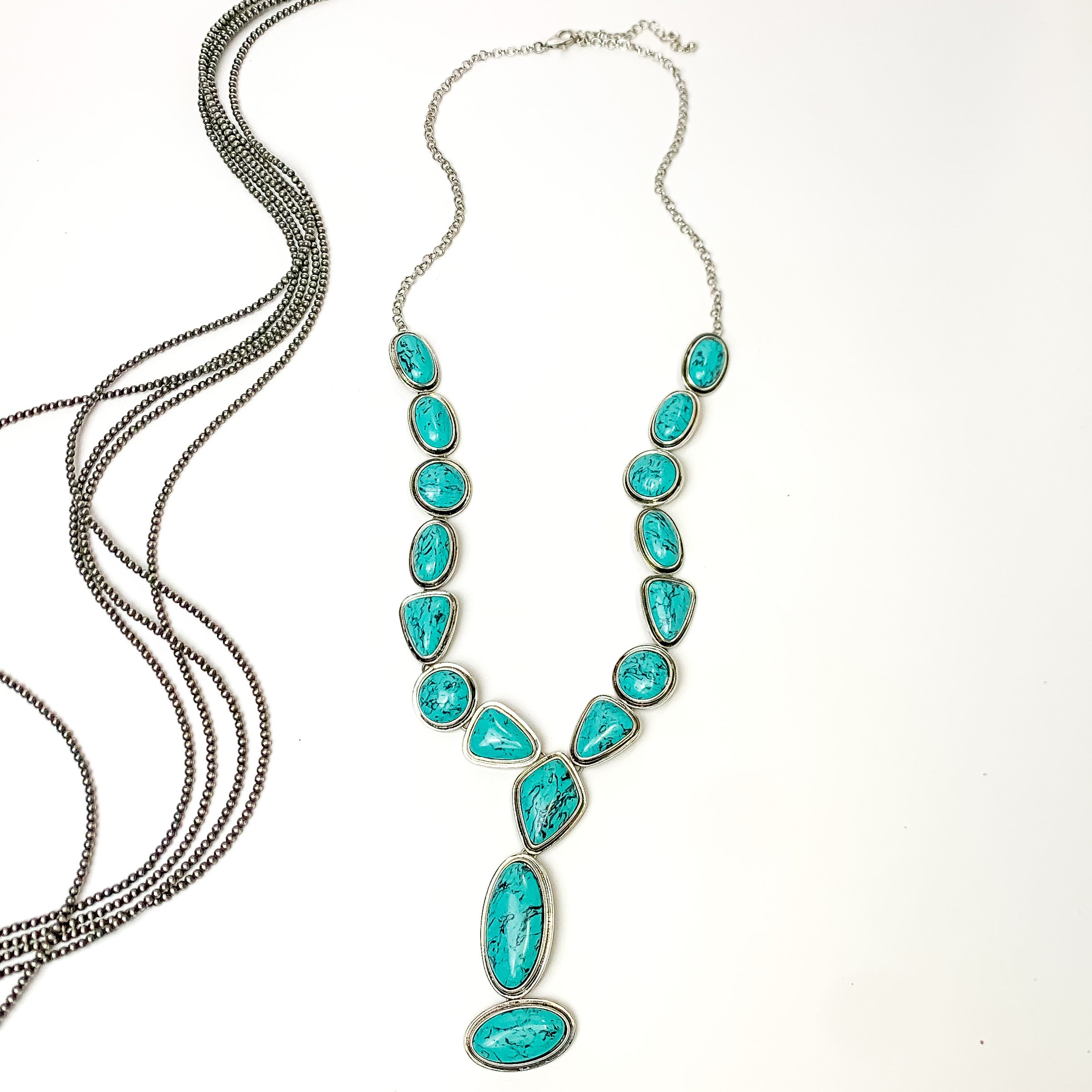 Multi stoned long necklace in turquoise with a dangling turquoise stones. Pictured on a white background with Navajo pearl stands.