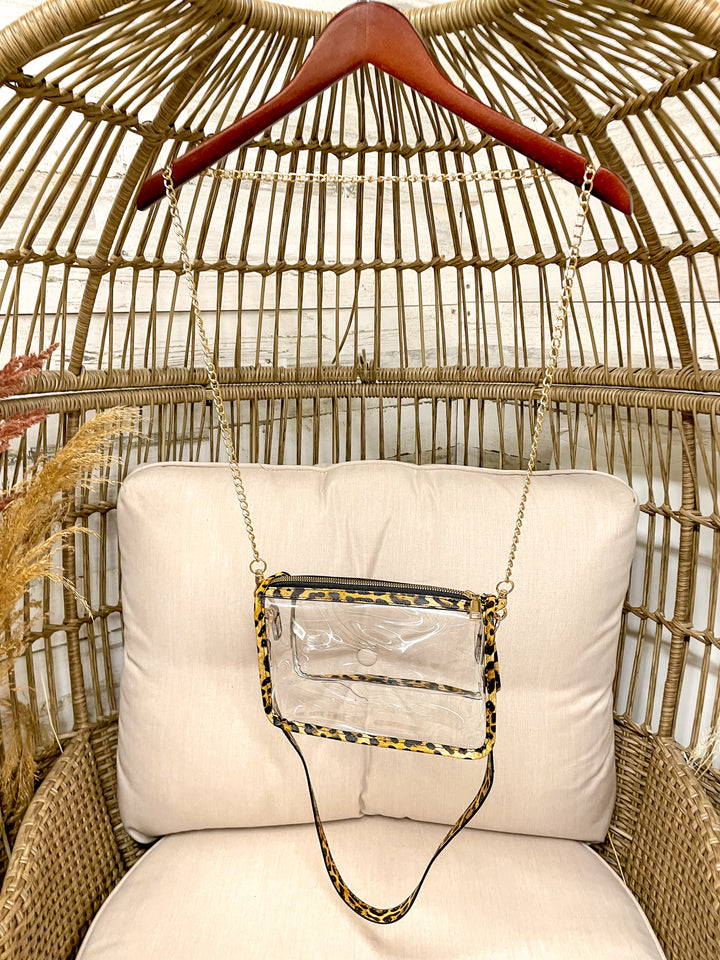 Clear handbag with leopard print accents on a cushioned chair