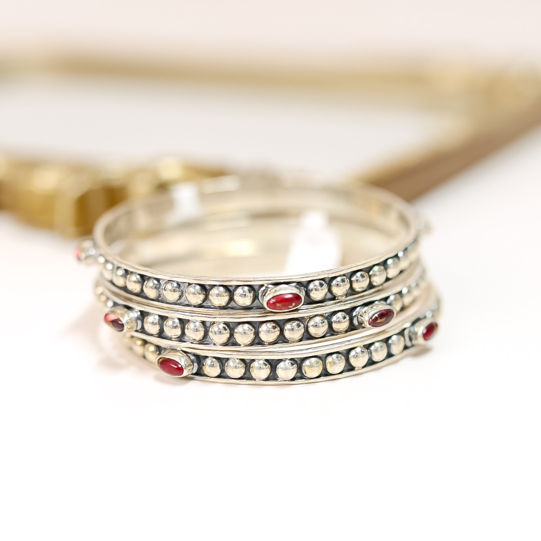 Stack of handmade sterling silver bangles featuring four pink Dahlia Rose stones on each, with beaded detailing.