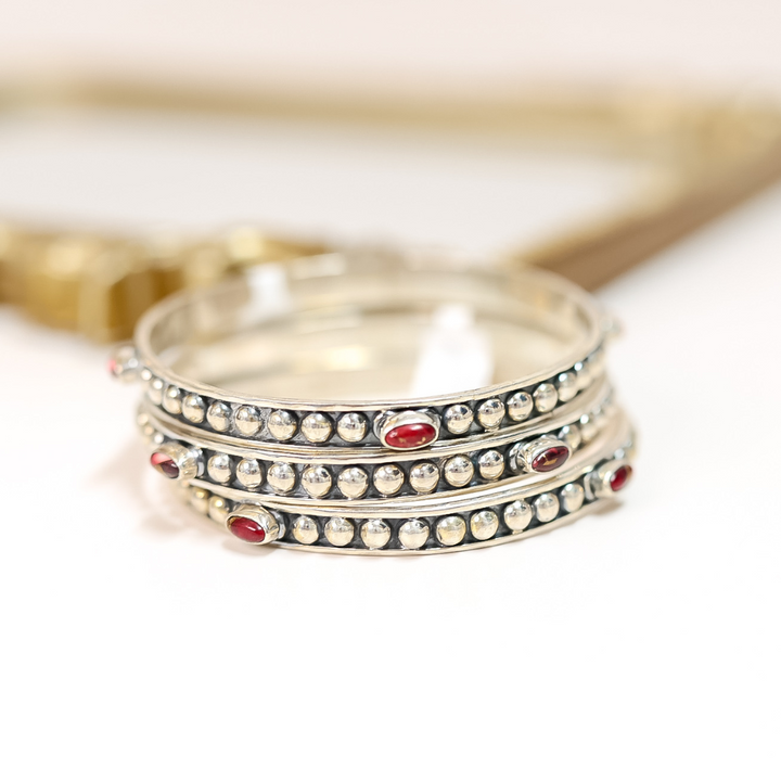 Stack of handmade sterling silver bangles featuring four pink Dahlia Rose stones on each, with beaded detailing.