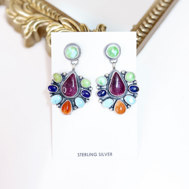 Multicolored teardrop earrings on a white card with 'Sterling Silver' text, gold frame in background