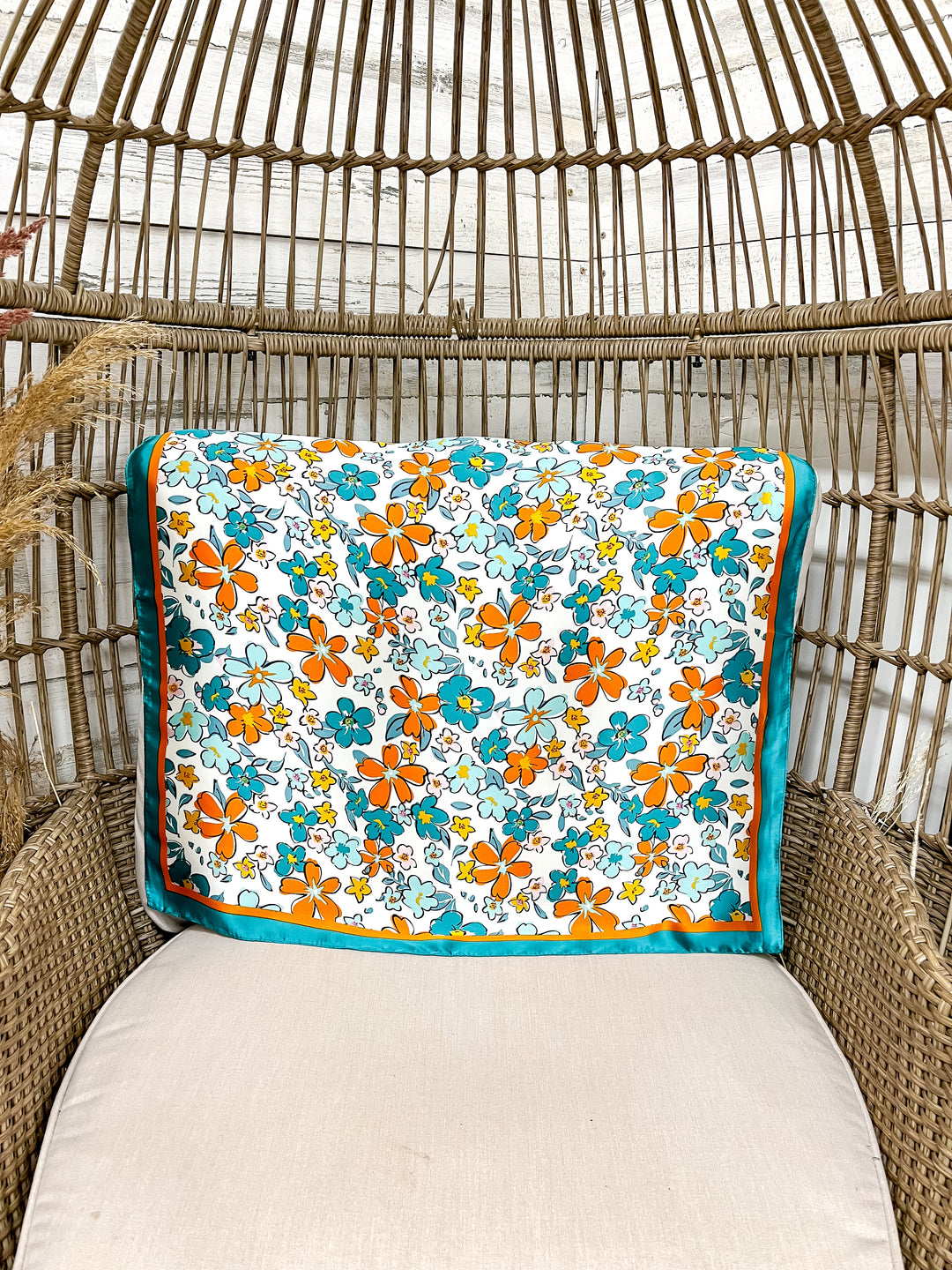 Floral-patterned scarf on a wicker chair with beige cushion