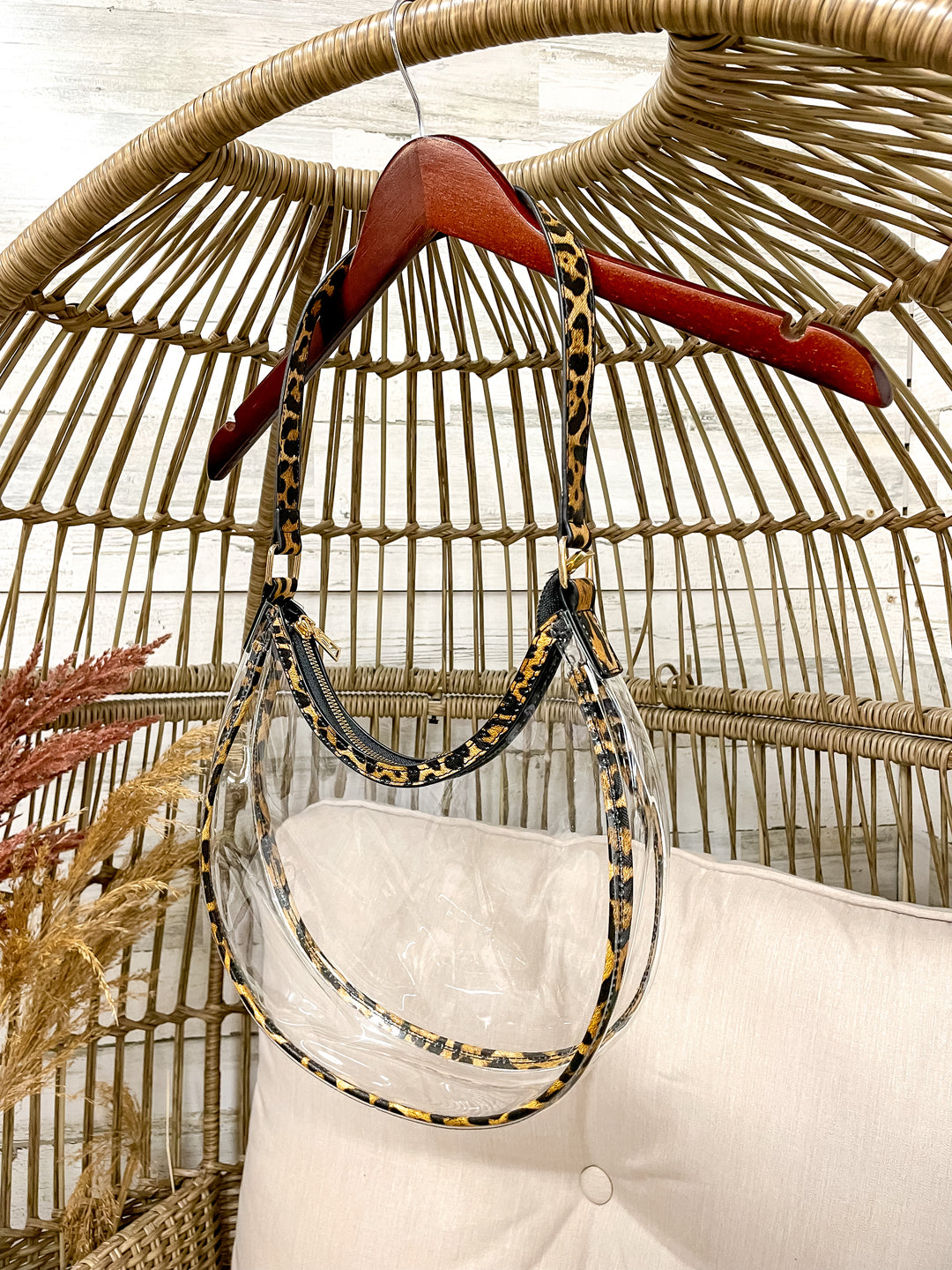 Clear stadium with gold trim hanging from a wicker chair on a hanger. 