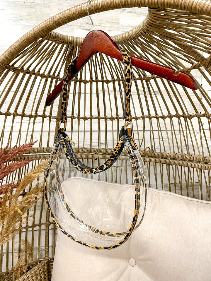 Clear stadium with gold trim hanging from a wicker chair on a hanger. 