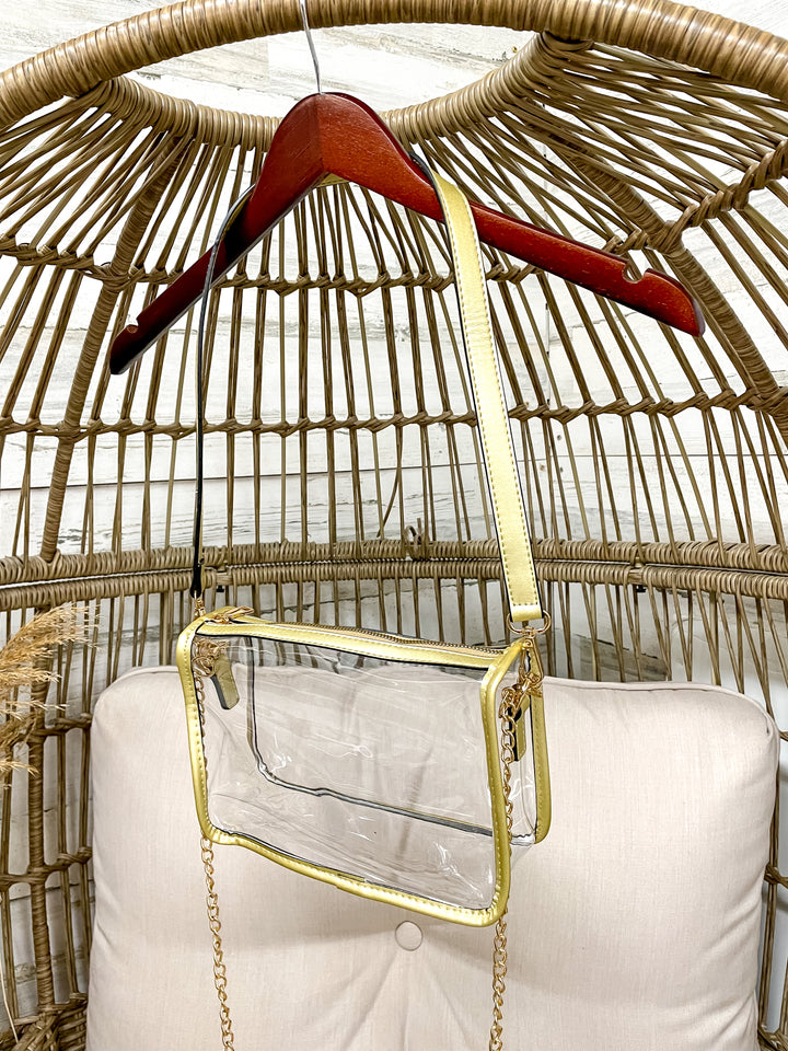 Clear handbag with gold chain detail on a wicker chair