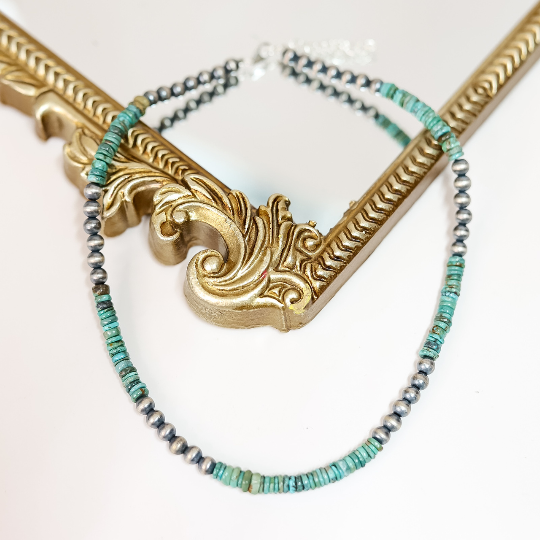 Hand-strung Red River turquoise and 6mm Navajo pearl necklace displayed on a mirror with gold frame; 16-inch length with 2-inch adjustable chain, boho western jewelry style.