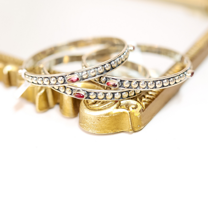 Stack of handmade sterling silver bangles featuring four pink Dahlia Rose stones on each, with beaded detailing.