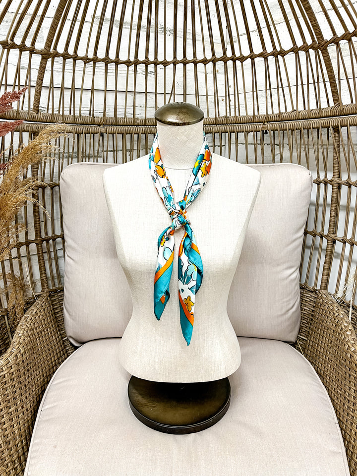 Mannequin with a colorful scarf draped over it, sitting on a white cushioned chair with a wicker backrest.
