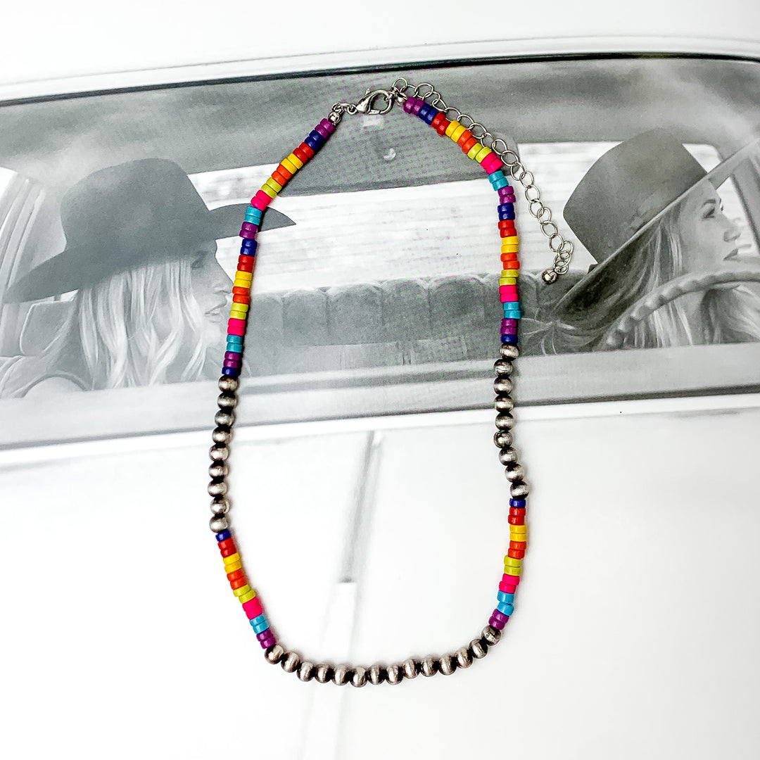 Multi color chip beaded necklace with faux Navajo pearls there are about nine next to each other on each side and one at the bottom. Pictured on a black and white photo.