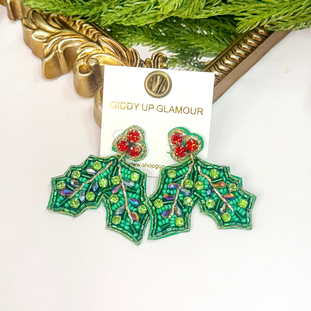 Green holly leaf earrings with red berries on a 'Giddy Up Glamour' card.
