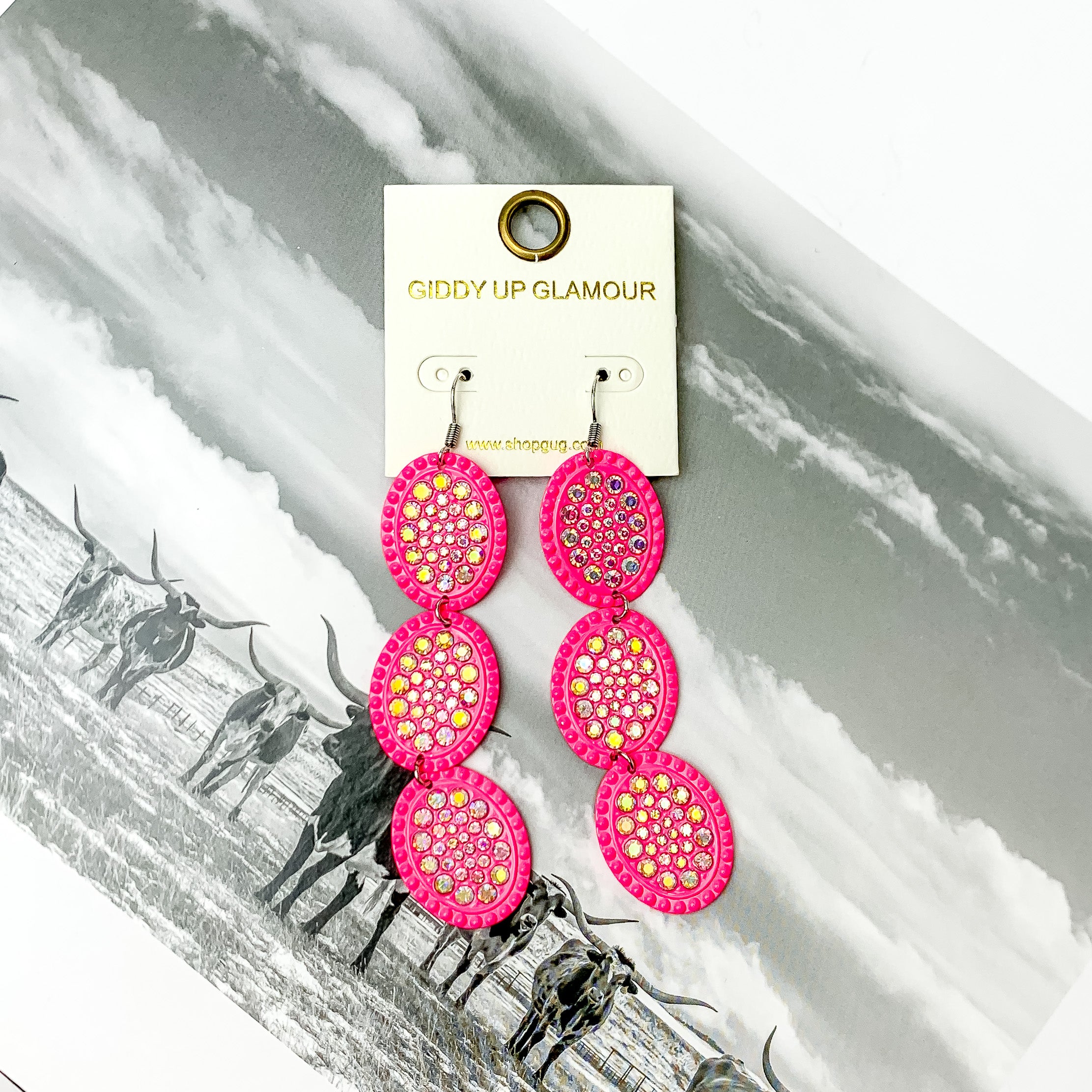 Pink three tier ab crystal oval shape dangle earrings with ab crystals. Pictured on a black and white western picture.