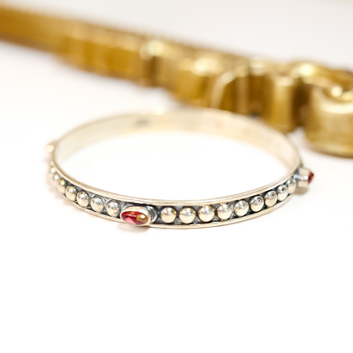 Silver bracelet with embedded stones on a white background