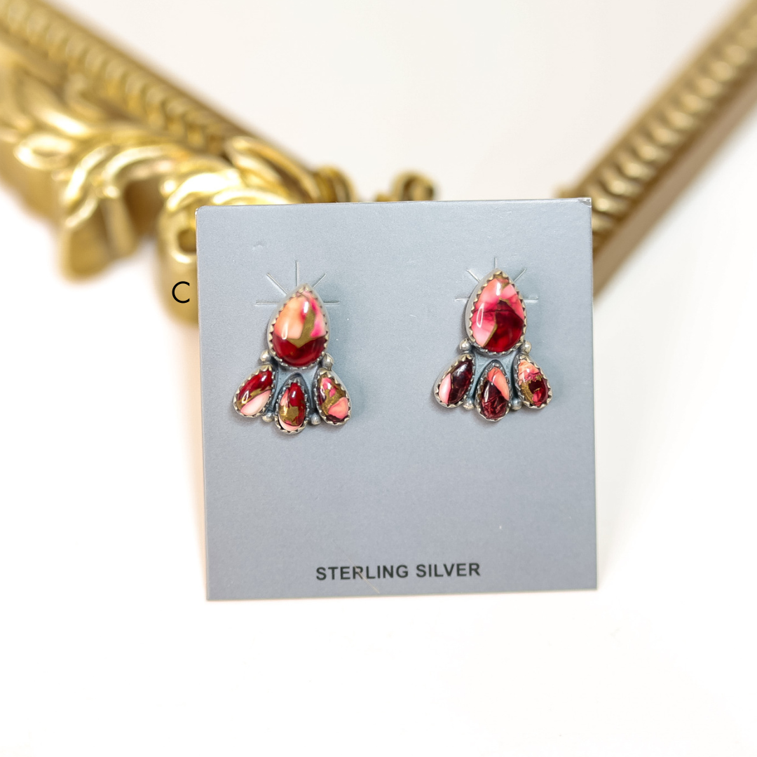 Pair of red gemstone earrings on a gray card with 'Sterling Silver' text, gold frame in background