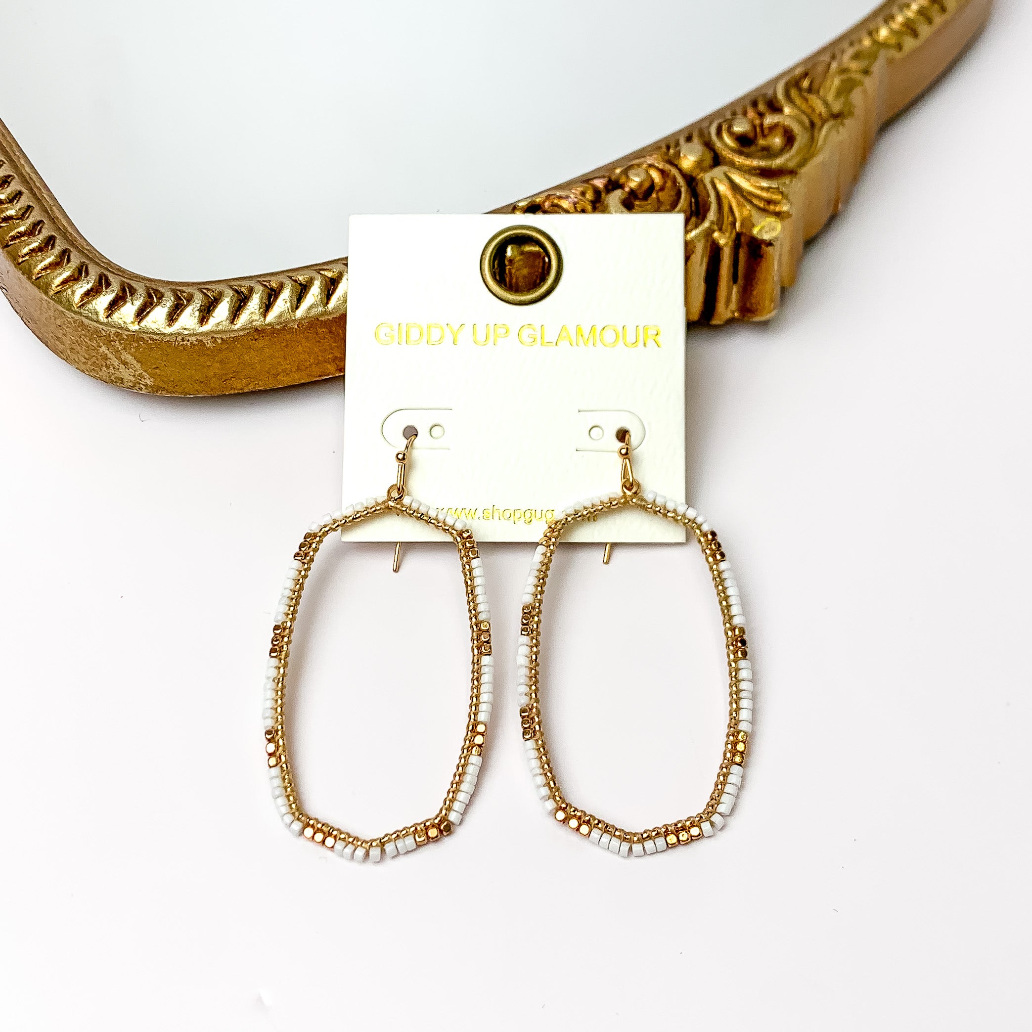 White Beaded Open Large Drop Earrings with Gold Tone Accessory. Pictured on a white background with a gold frame through it.
