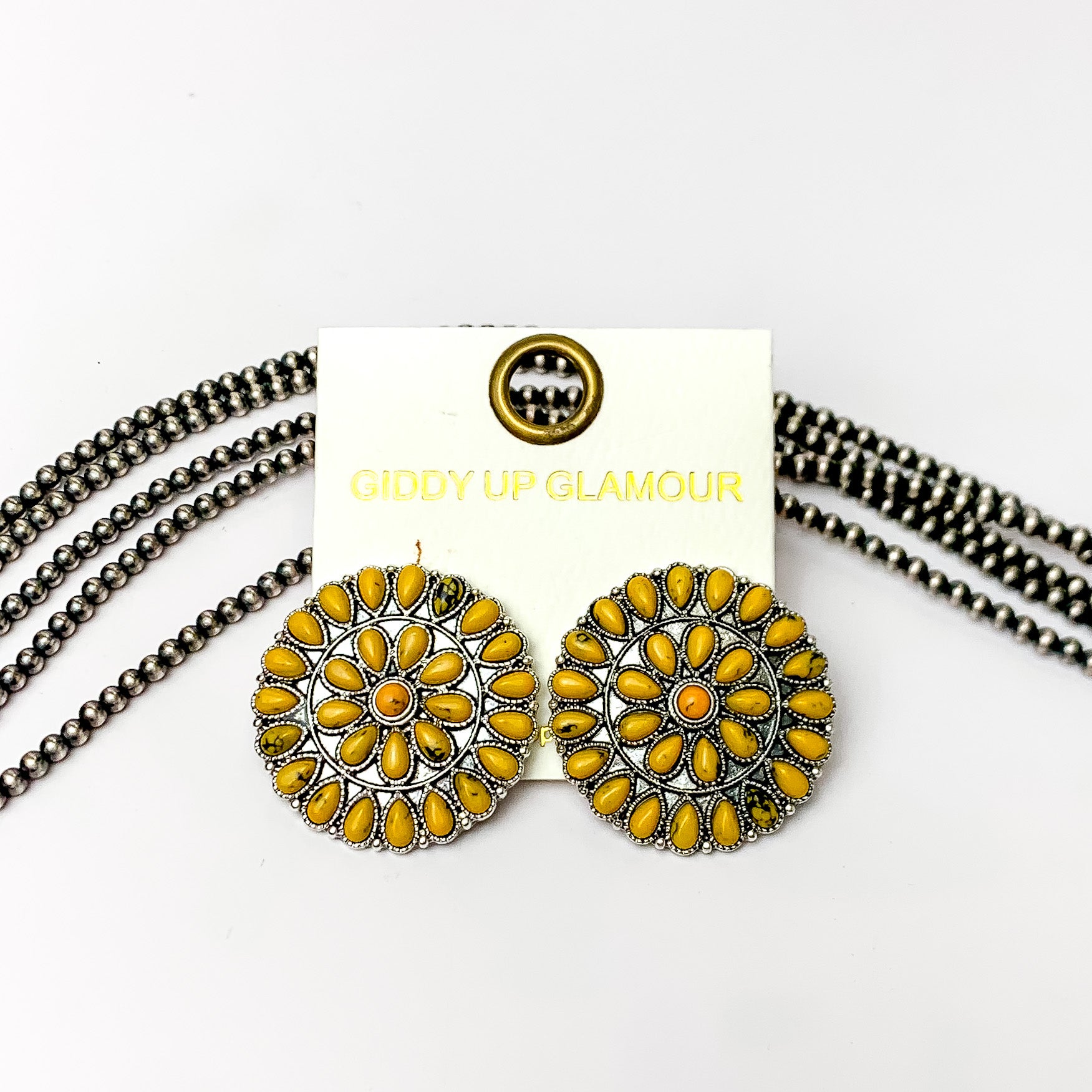 Silver Tone Circle Cluster Stud Earrings with Yellow Stones. Pictured on a white background with beads through the background.