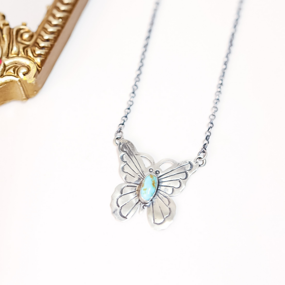 Butterfly-shaped necklace with a gemstone on a white background