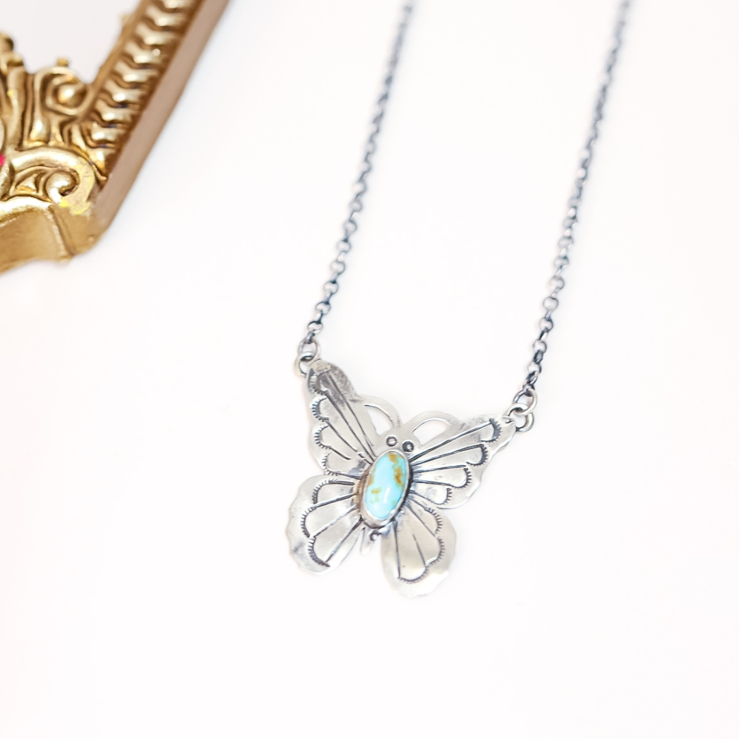Butterfly-shaped necklace with a gemstone on a white background