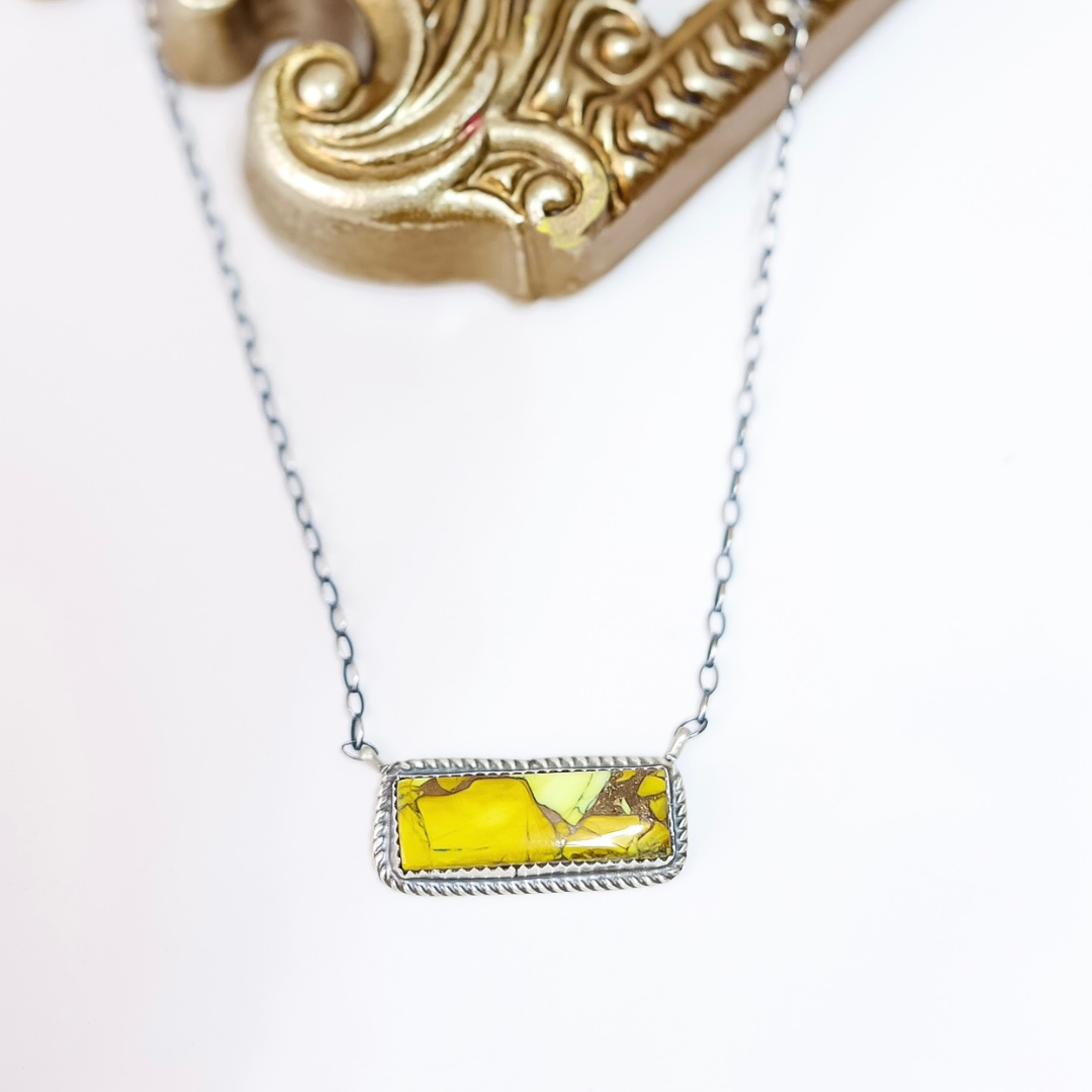 Sterling silver necklace with horizontal Honey Dahlia stone bar pendant handcrafted by Donovan Nez on white background with gold mirror detail.