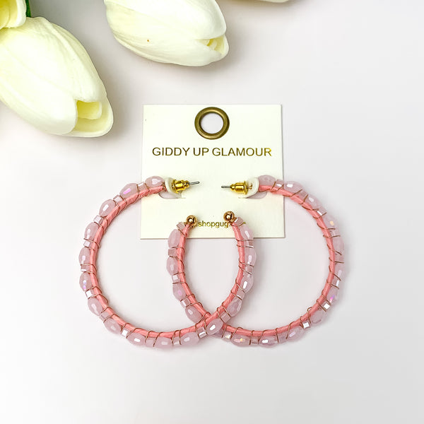 Large Hoops Outlined with Crystals in Light Pink. Pictured on a white background with white flowers in the top left corner.