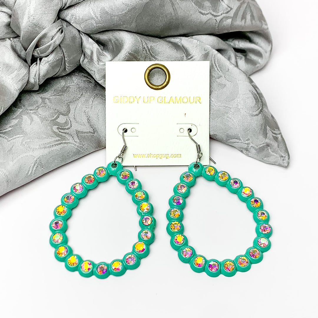 Open Teardrop Earrings with AB Crystal Outline in Turquoise. Pictured on a white background with silver fabric behind the earrings.