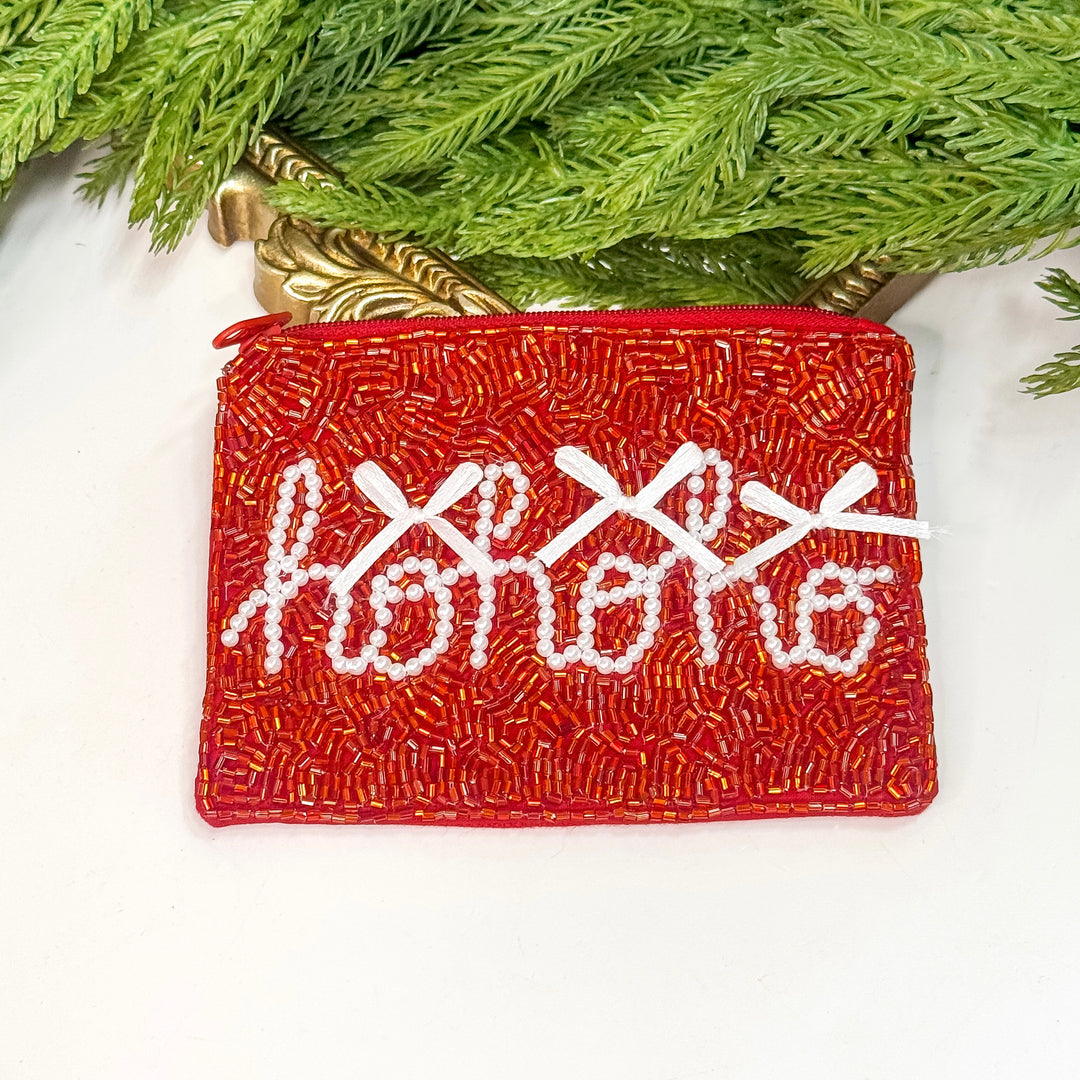 Red beaded pouch with 'Happy Holidays' embroidery on a white surface with greenery.