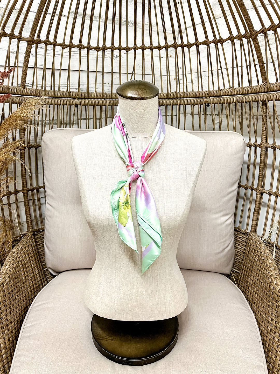 Mannequin with a colorful scarf draped over it, sitting on a wicker chair.