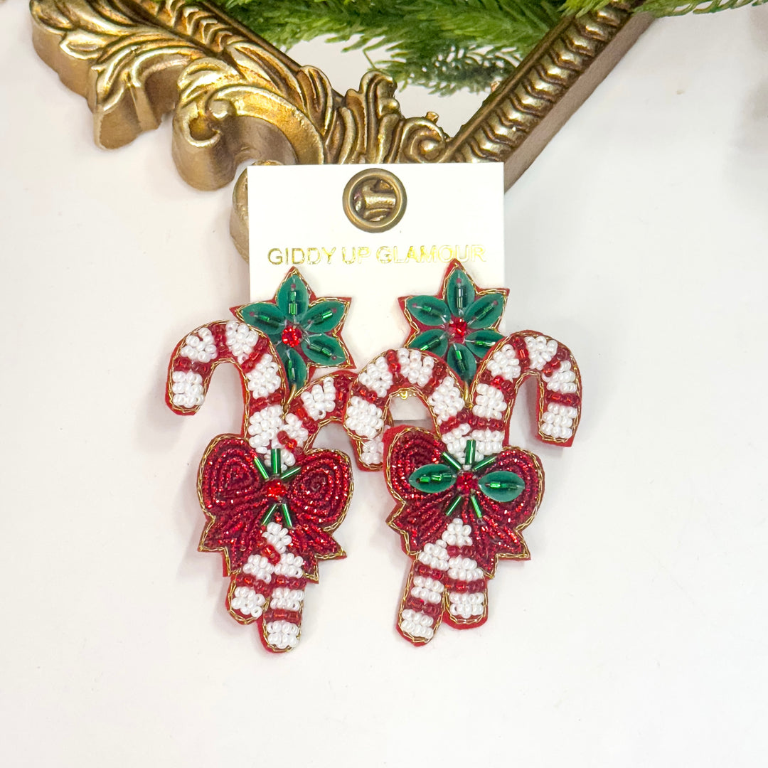 Christmas-themed earrings with candy canes and bows on a white background