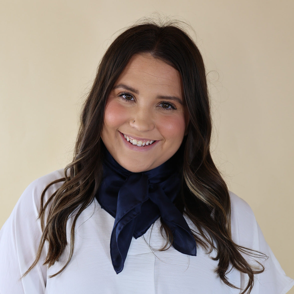 Brunette model is pictured wearing a white, Drop shoulder top with a Solid Navy Blue scarf tied around her neck. Model is pictured in front of a beige background.