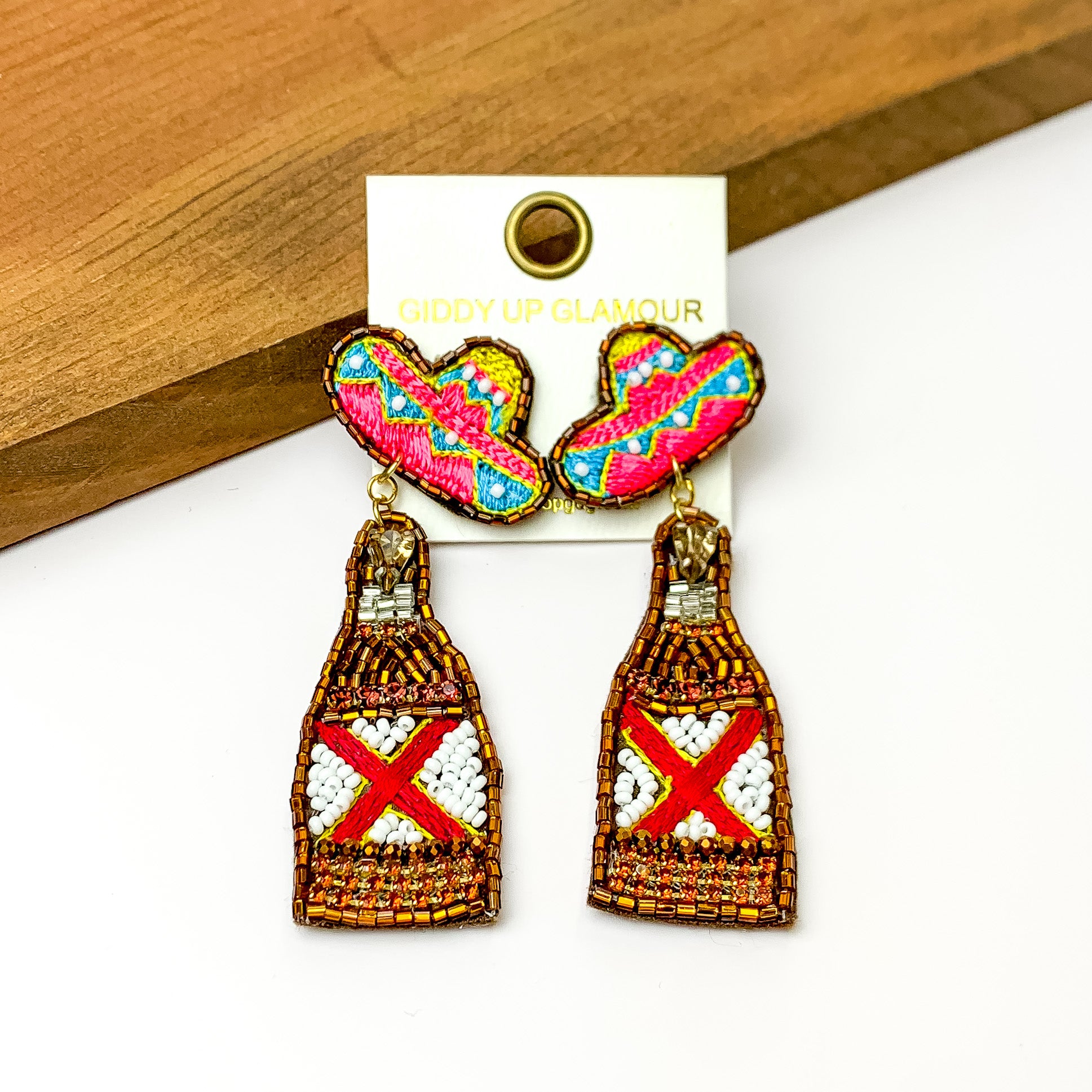 Beaded Gold Beer Bottle Earrings with Sombrero Studs. Pictured on a white background with a wood piece at the top.
