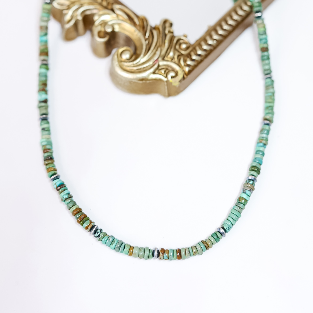 Handmade Red River Turquoise necklace with sterling silver saucer Navajo pearls on white background with ornate gold frame.