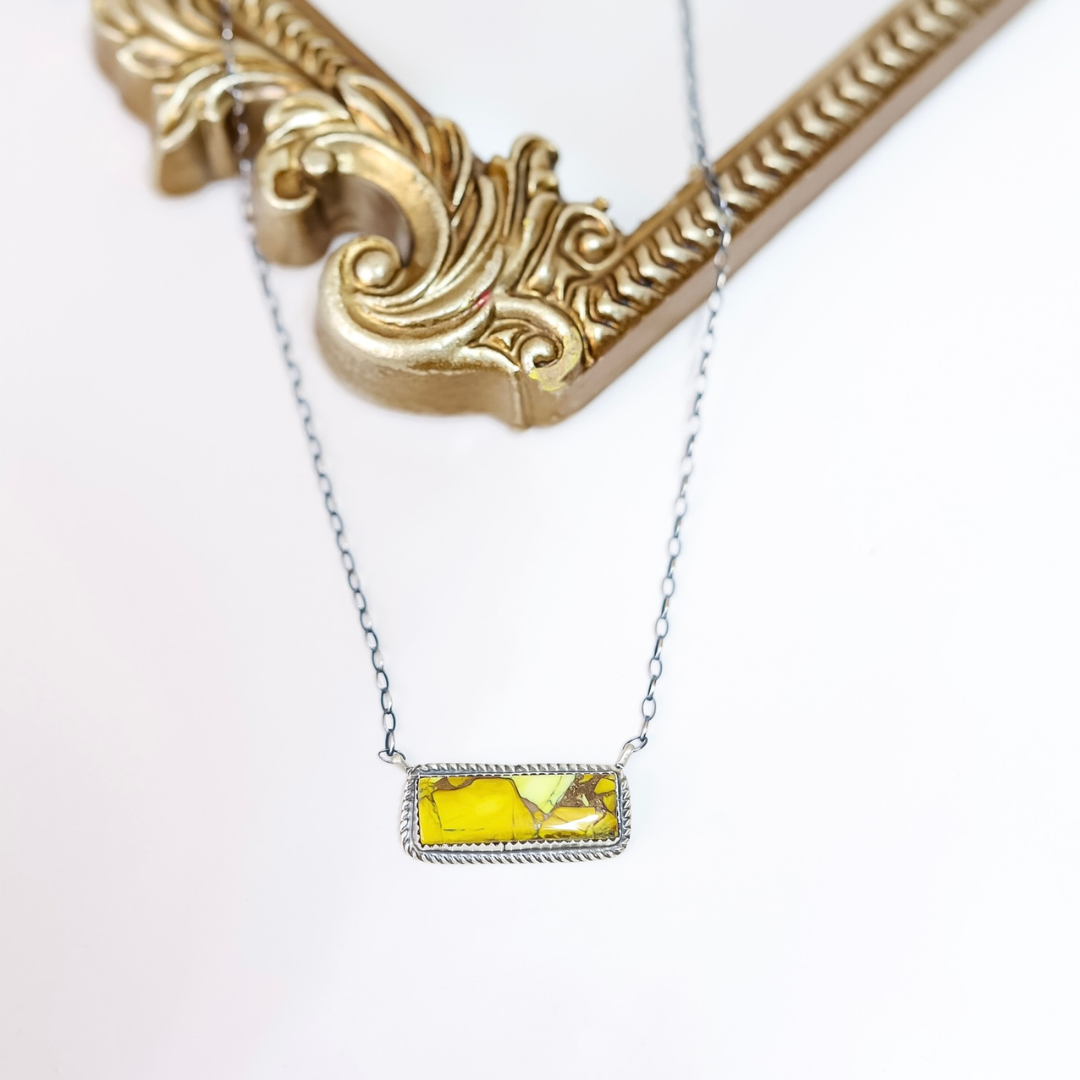Sterling silver necklace with horizontal Honey Dahlia stone bar pendant handcrafted by Donovan Nez on white background with gold mirror detail.