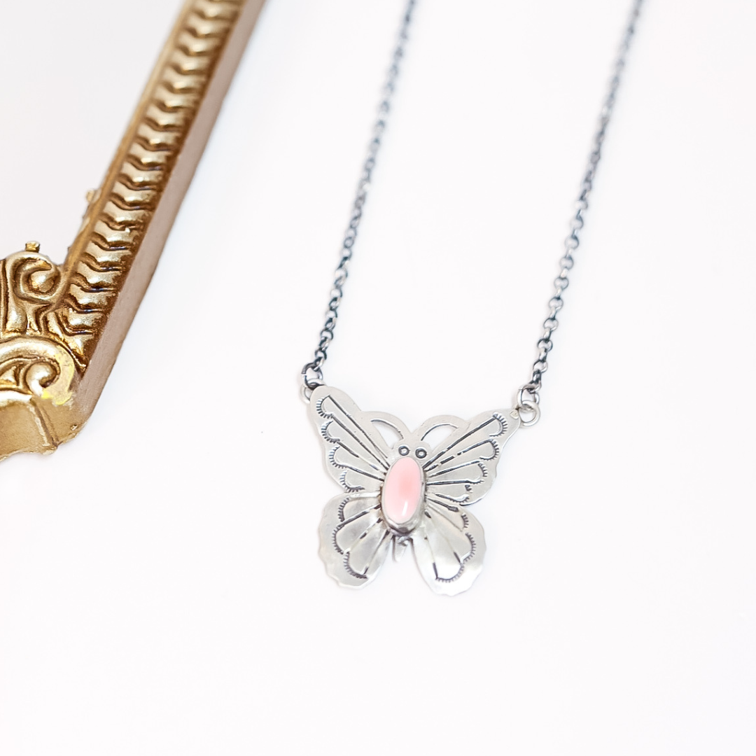 Butterfly necklace with pink center on a white background