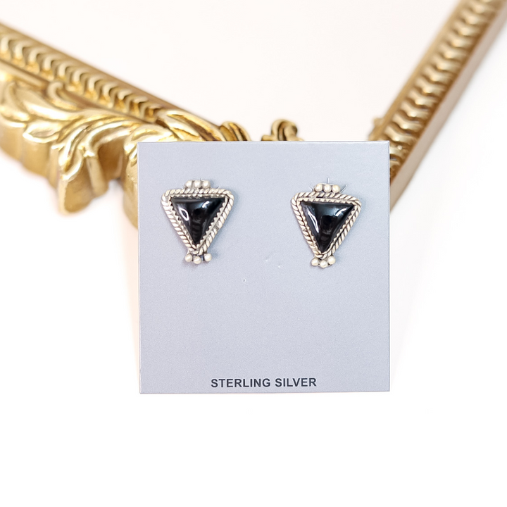 Triangle-shaped earrings on a card with 'Sterling Silver' text, gold mirror in background