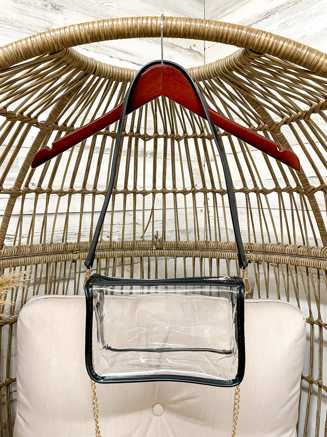 Clear handbag with a red hanger on a wicker chair