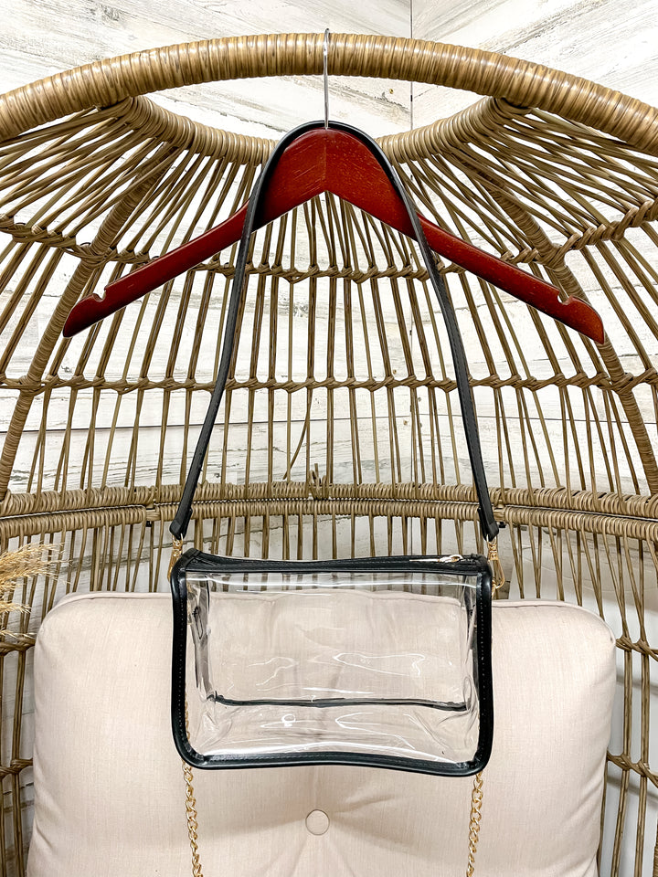 Clear handbag with a red hanger on a wicker chair