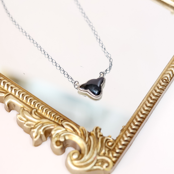 Sterling silver necklace featuring a black onyx cow head silhouette pendant on a 20-inch chain, styled with a vintage gold mirror.