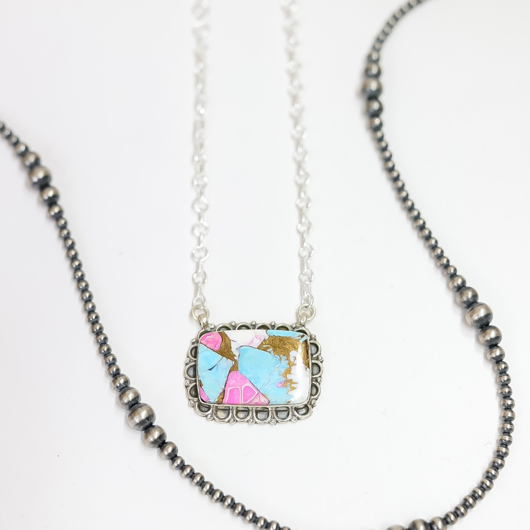 Close-up of a rectangular handmade necklace with pink, turquoise, and white stone inlay, framed in sterling silver on a 20-inch adjustable chain.