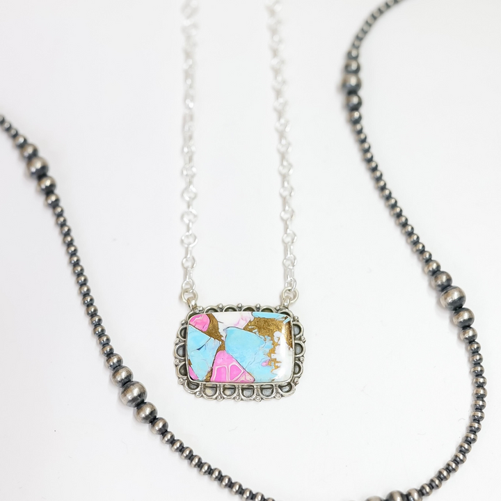 Close-up of a rectangular handmade necklace with pink, turquoise, and white stone inlay, framed in sterling silver on a 20-inch adjustable chain.